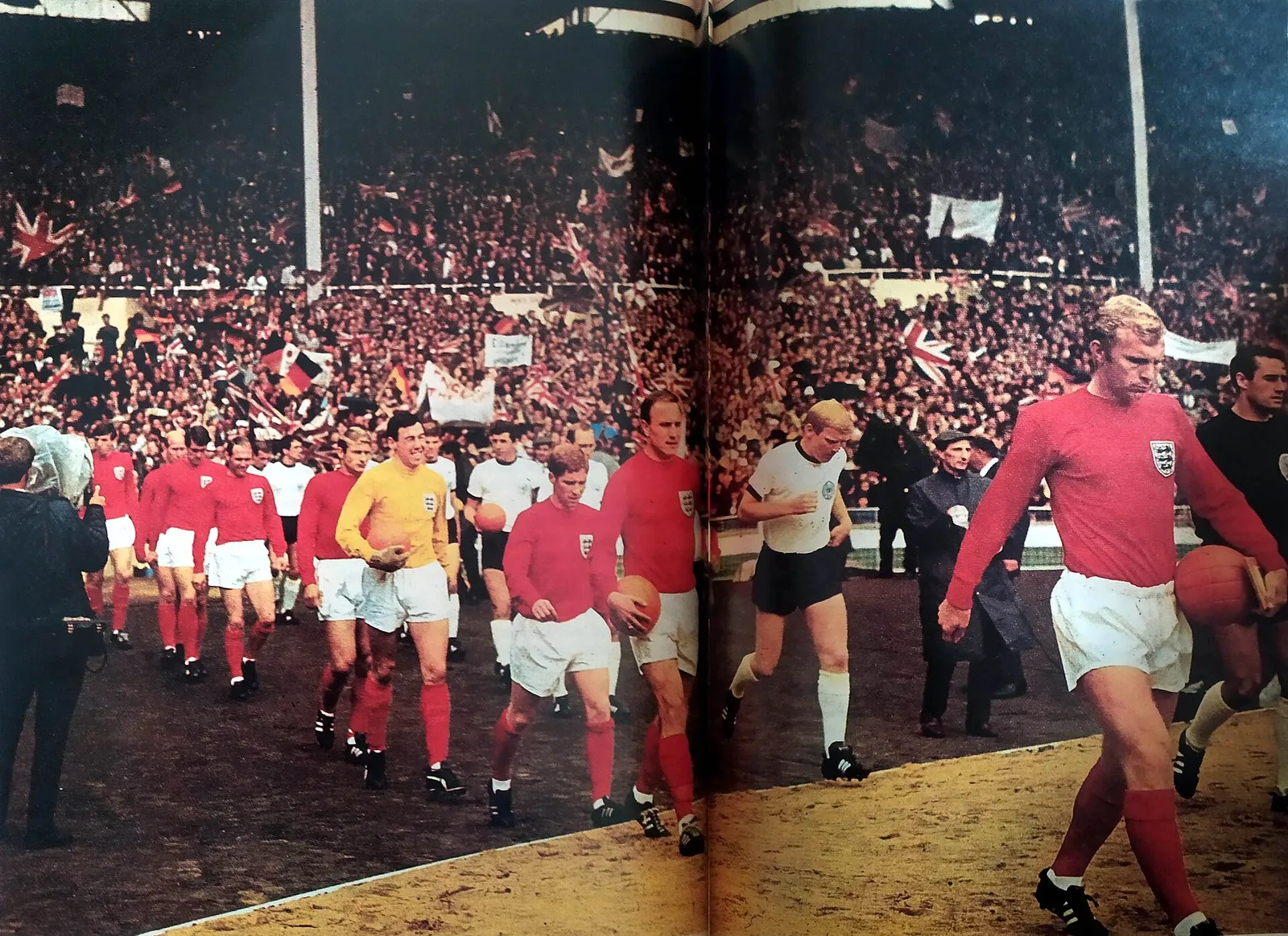 A Inglaterra, de vermelho e liderada pelo capitão Bobby Moore, e a Alemanha Ocidental entram no gramado de Wembley para a final, em 30 de julho de 1966.